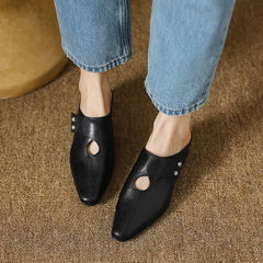 Black leather mule with side cutout and stud detail, worn with rolled jeans and low heel