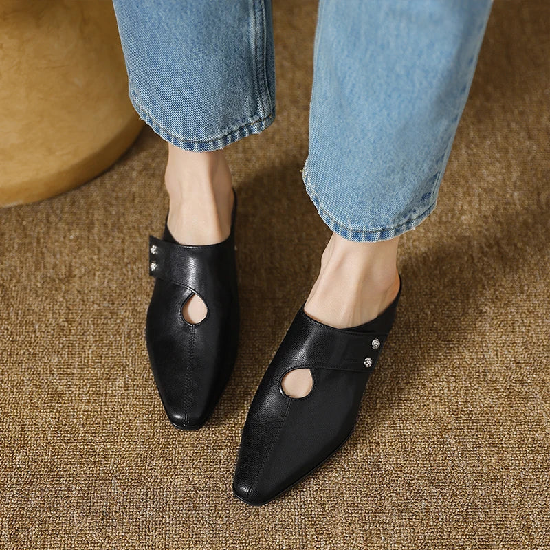 Black leather mule with side cutout and stud detail, worn with rolled jeans and low heel