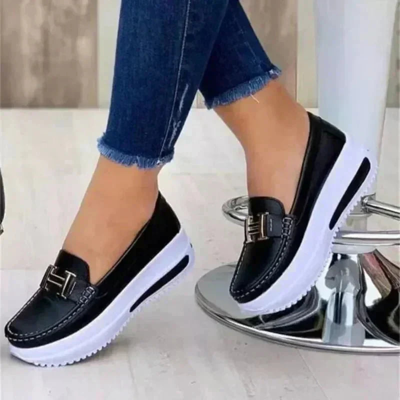 Sleek orthopedic loafers, black slip-on with buckle strap and white sole.