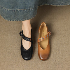 Black leather flats with ankle strap, buckle, and star-flower charm accents