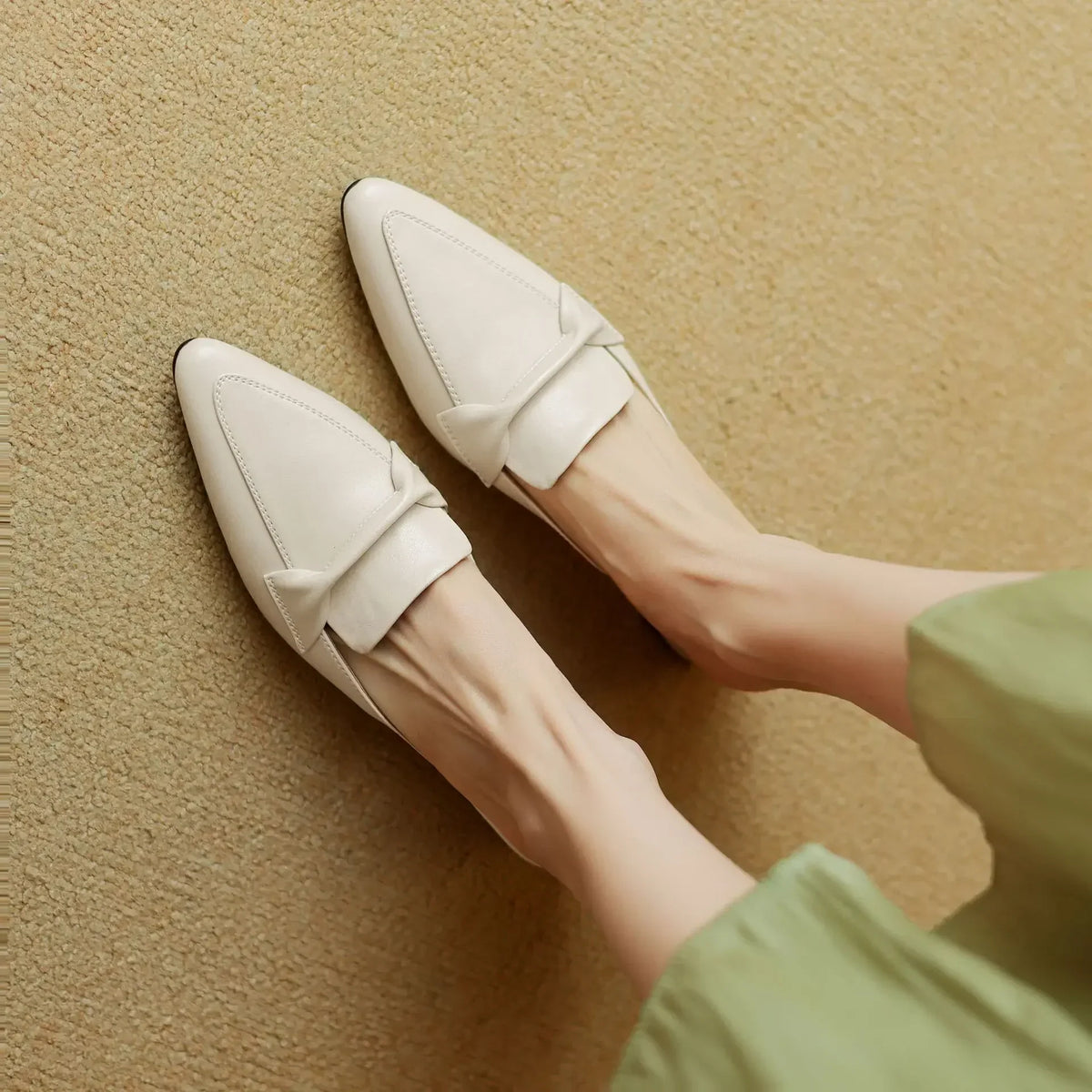 Pair of beige mules showing front slip-on strap and pointed toe