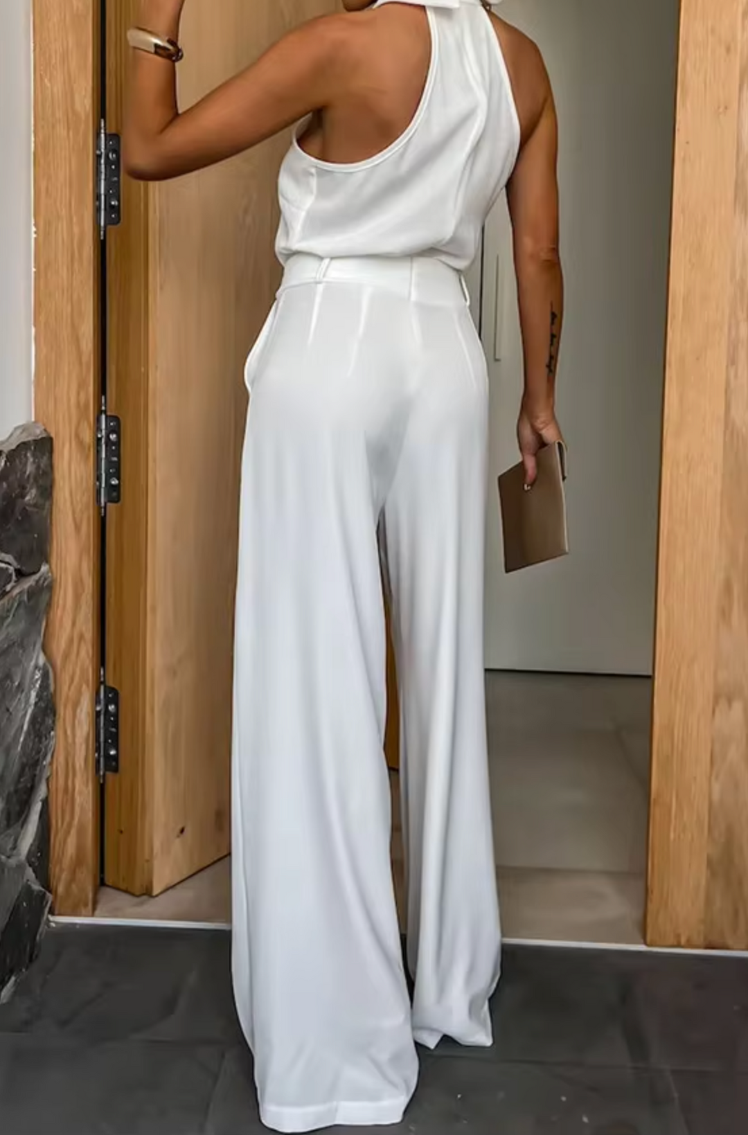 White halter jumpsuit with sleeveless cut and wide-leg pants, smooth waist seam.