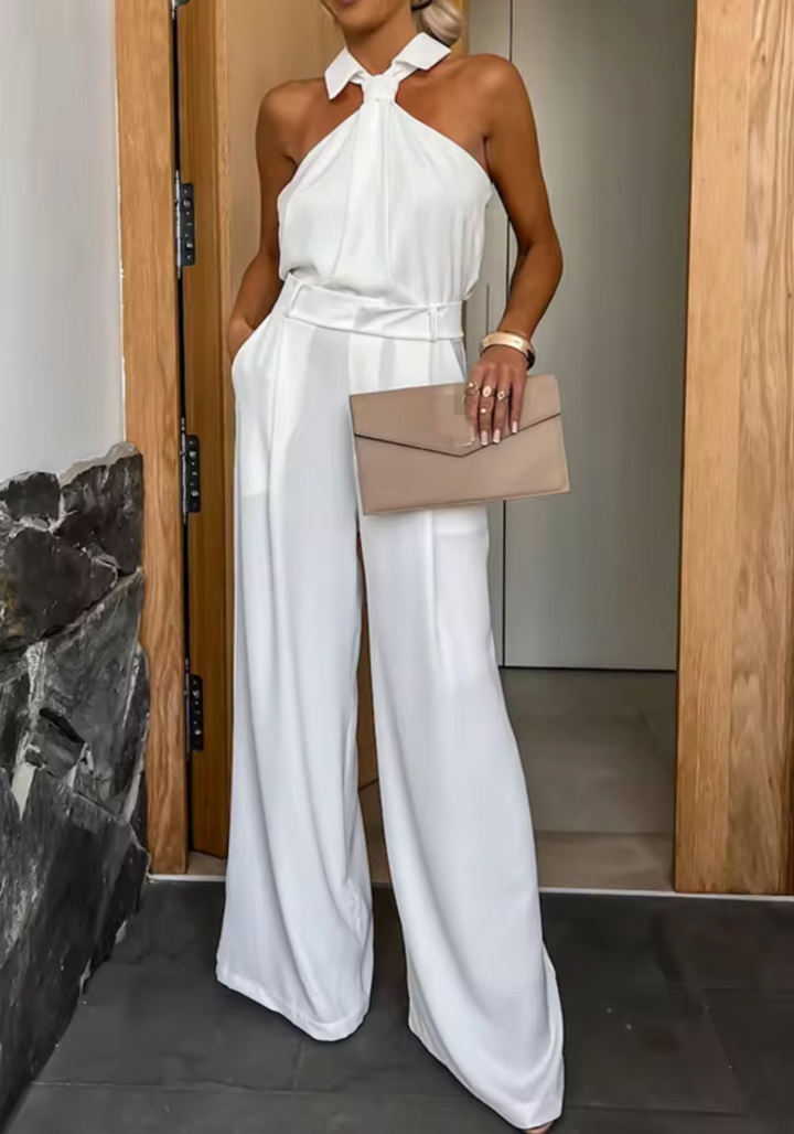 White halter jumpsuit with bow neck detail and wide-leg trousers, fitted waist belt.
