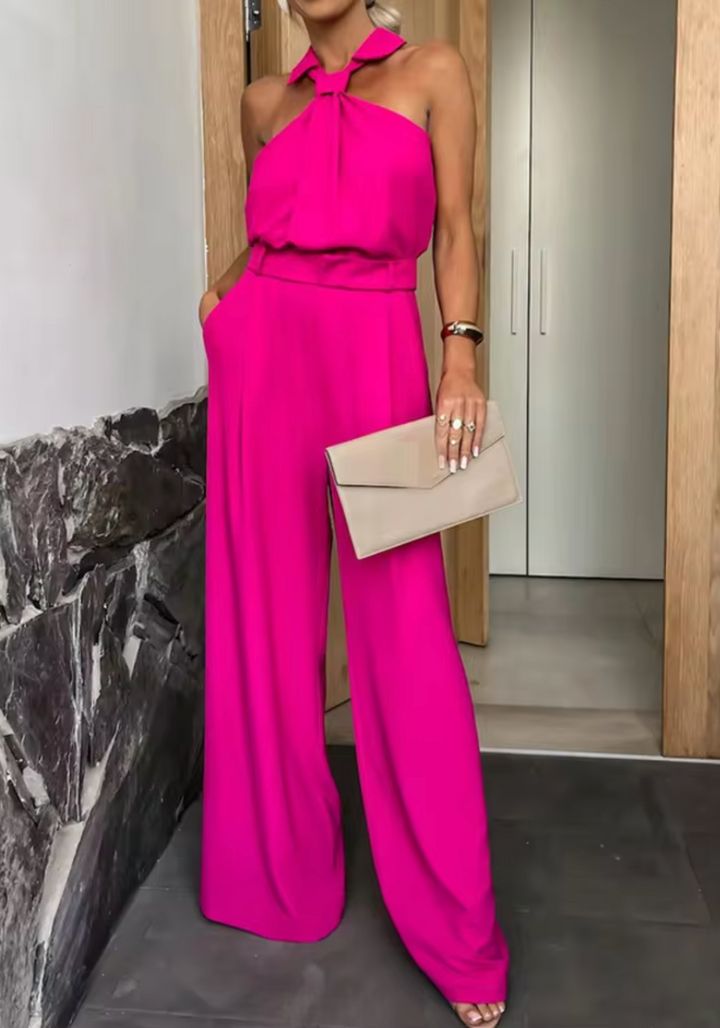 Bright pink halter jumpsuit with bow neck and wide-leg pants, sleeveless belted fit.