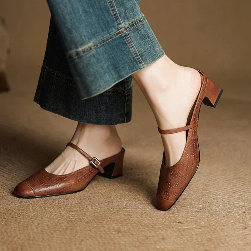 Brown leather mules with ankle strap and low block heel worn with cuffed jeans