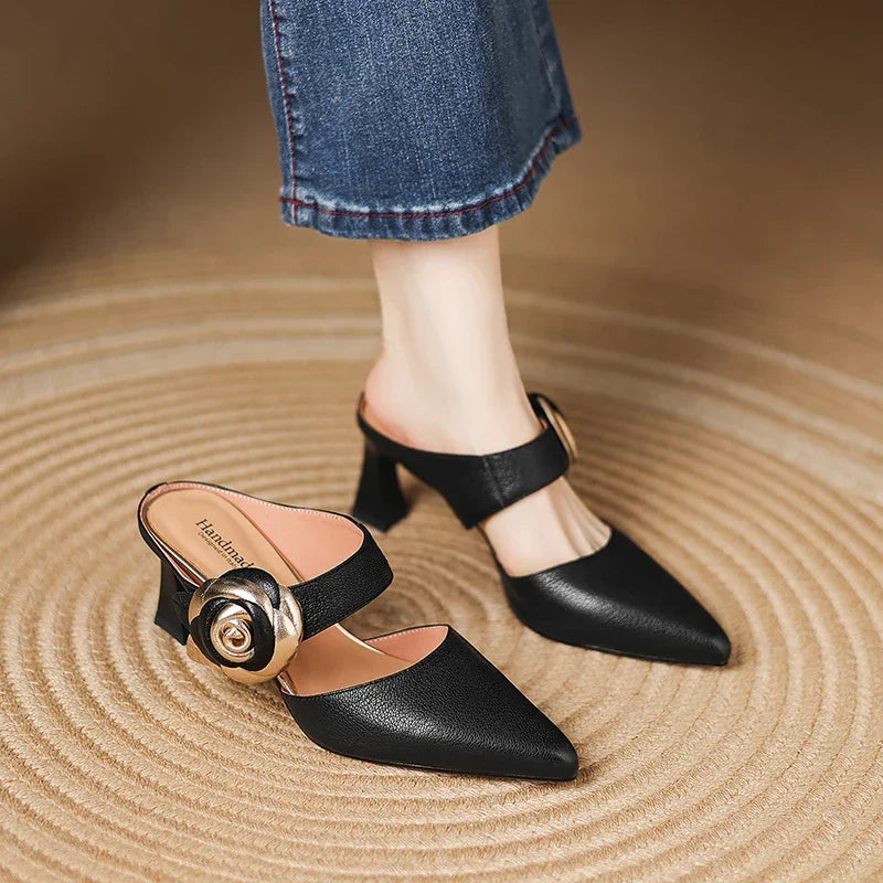 Black genuine leather heels with pointed toe, ankle strap, and gold rosette buckle detail