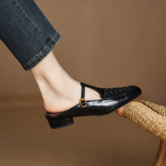 Black leather mule with lace-up front and round strap detail at the vamp