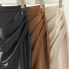 Three leather midi skirts on hangers in black, tan, and cream