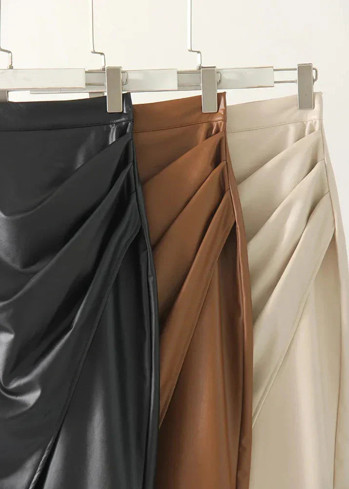 Three leather midi skirts on hangers in black, tan, and cream