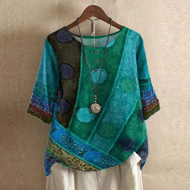 Women’s colorful floral blouse, teal with circular patch print, short sleeves.