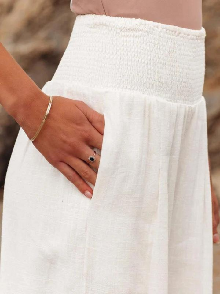 White loose pants close-up with elastic smocked waistband and gathered flowing fabric