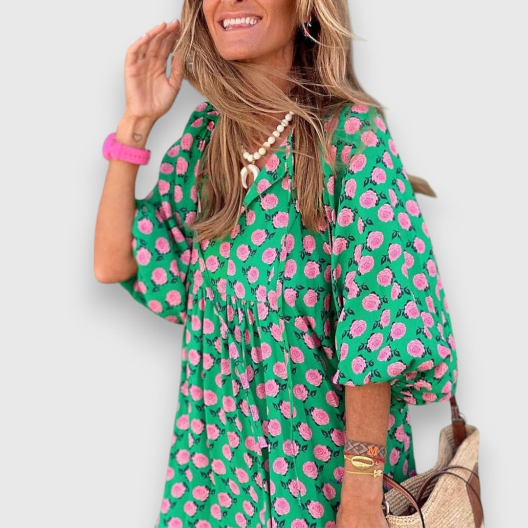 Loose breathable dress in green with pink floral print, V-neck and puff sleeves.