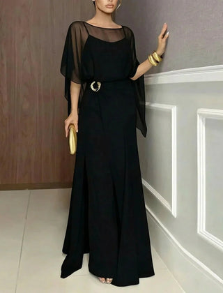 Black long jumpsuit with sheer overlay cape sleeves and ring-buckle waist detail.