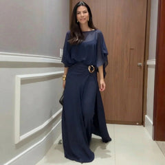 Navy long jumpsuit with sheer overlay cape sleeves and ring-buckle waist detail.