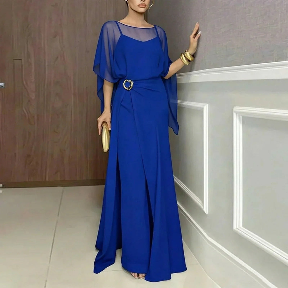 Blue long jumpsuit with sheer overlay draped sleeves and circular ring-belt.