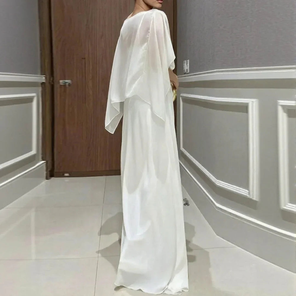 White long jumpsuit with sheer overlay draped sleeves and ring-buckle waist.