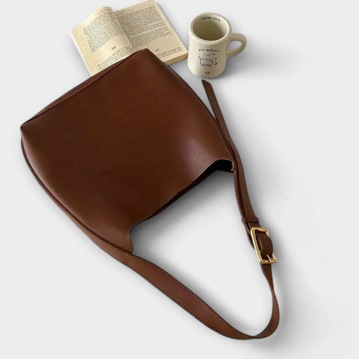 Brown leather shoulder bag with adjustable strap and gold-tone metal buckle