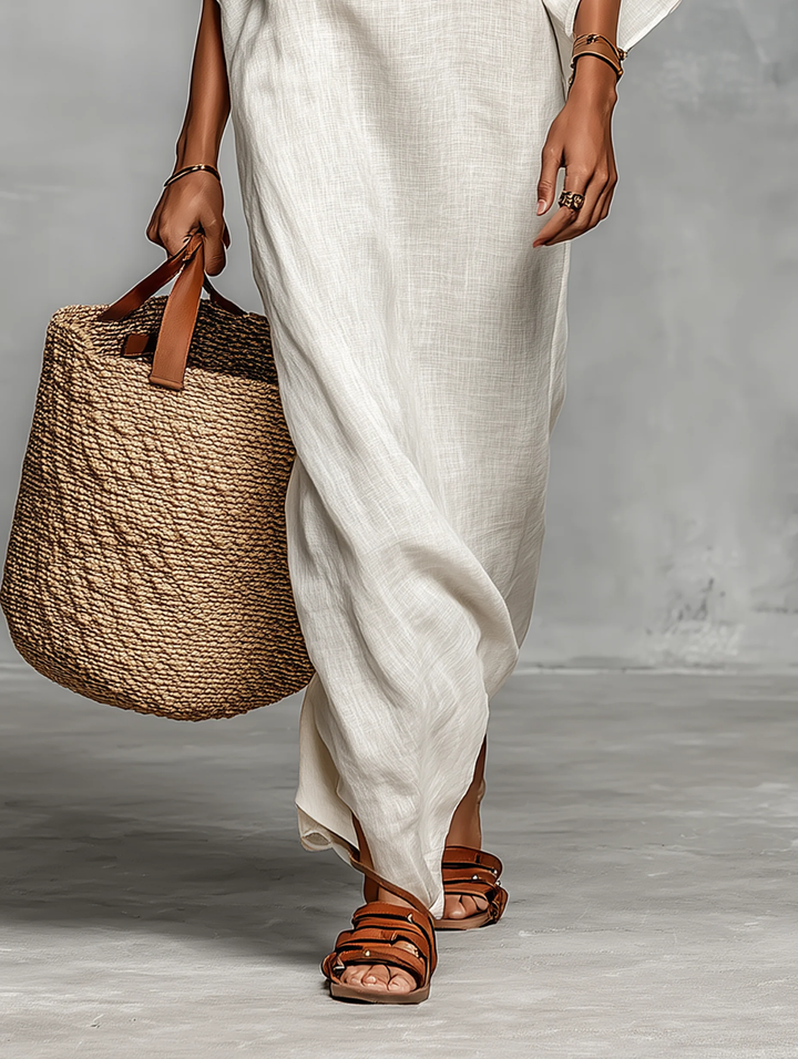 White linen maxi dress with draped off-shoulder design and black striped neckline band