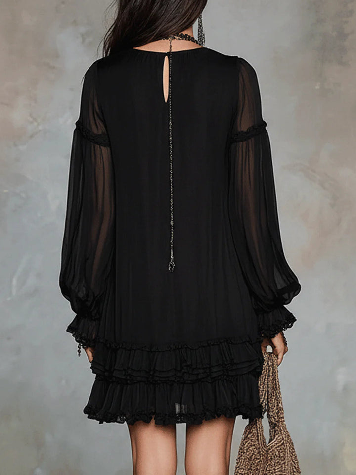 Black mini dress back view with sheer long sleeves and dangling chain detail