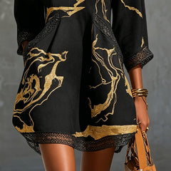 Black mini dress close-up: gold abstract print with crochet lace trim at hemline