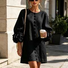 Black button-down mini dress with vertical buttons and large rosette sleeve cuffs