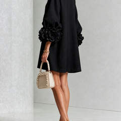 Black button-down mini dress with vertical button placket and rose-like cuff accents