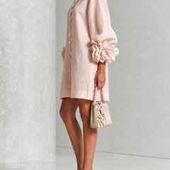 Blush pink button-down mini dress with button detail and rosette puff sleeves on side view
