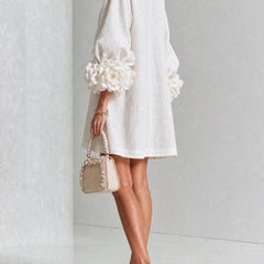 White button-down mini dress with large rosette cuff sleeves and gold buttons