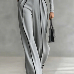 Grey wide-leg pants and high-neck long-sleeve top with white piping and waist belt buckle.