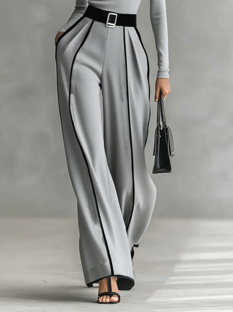 Grey wide-leg pants and high-neck long-sleeve top with white piping and waist belt buckle.