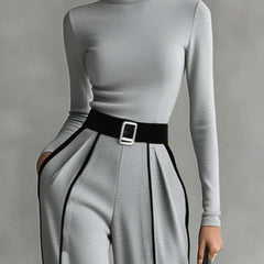 Grey high-neck long-sleeve top with waist belt buckle and pleated wide-leg pants with white trim.