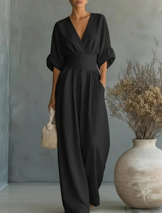 Black V-neck wide-leg jumpsuit with gathered waist and flowing full-length legs
