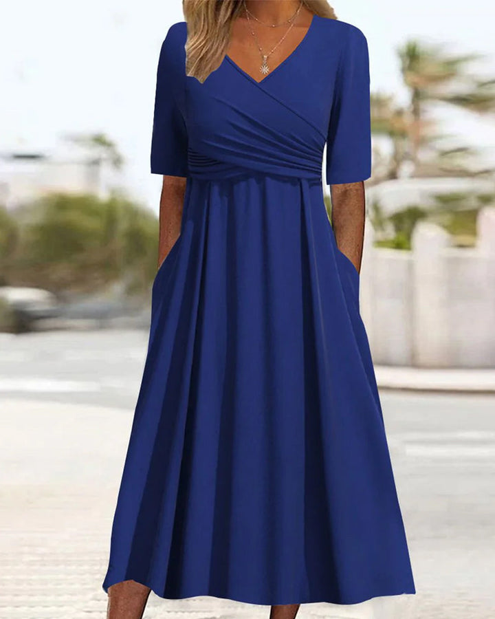 Blue crossover dress with short sleeves, V-neck, gathered waist, and flared skirt.