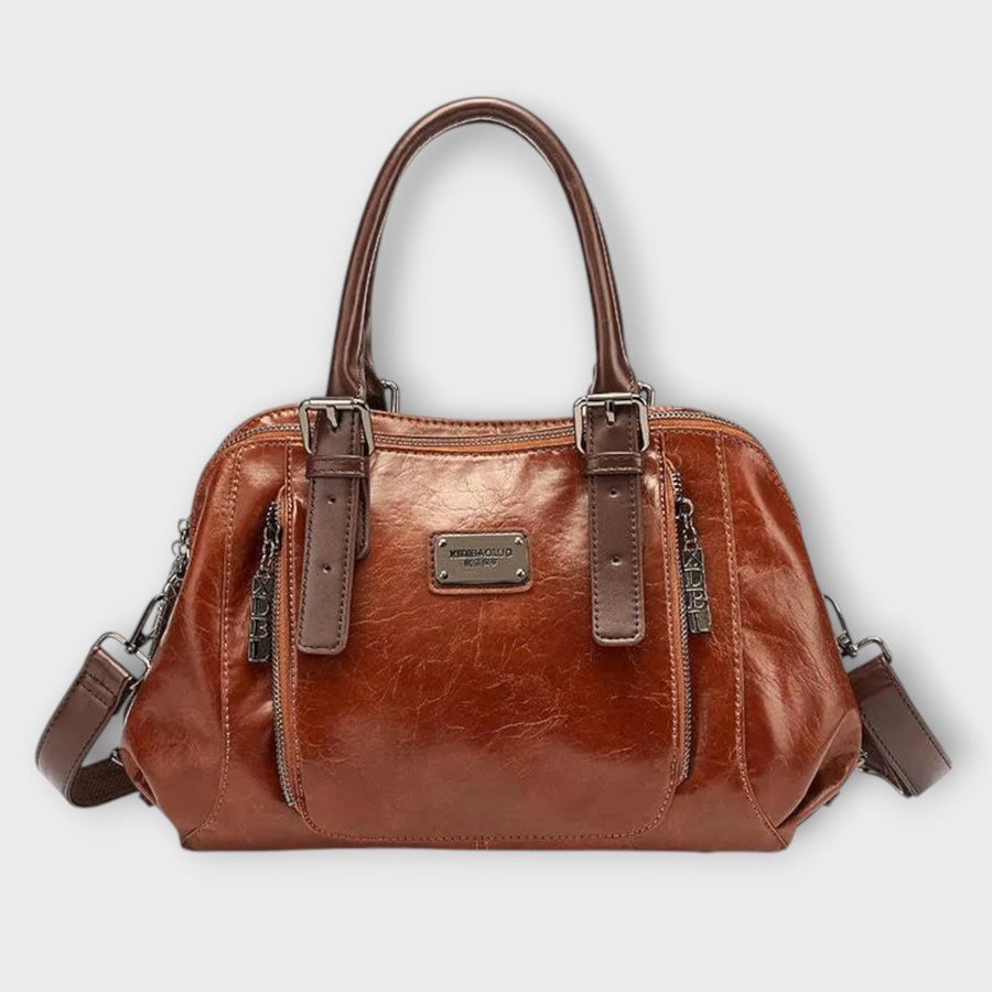 Tan leather-look shoulder bag with top handles, front logo plaque, zip top, crossbody strap.