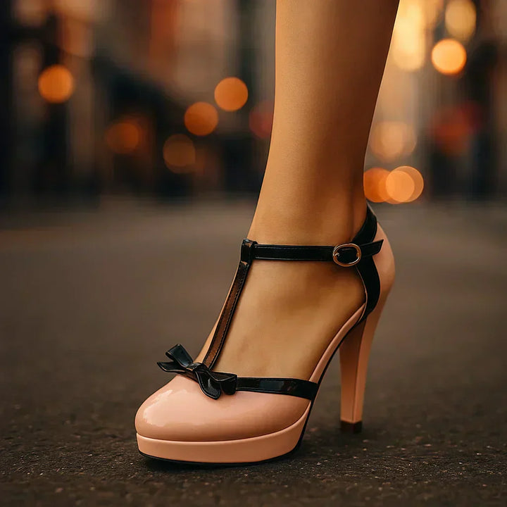 Estelle tie-strap heels in blush pink patent with black ankle strap and bow detail