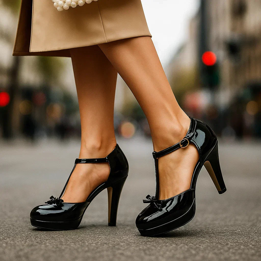 Estelle tie-strap heels in classic black patent with ankle strap, buckle ring, and bow