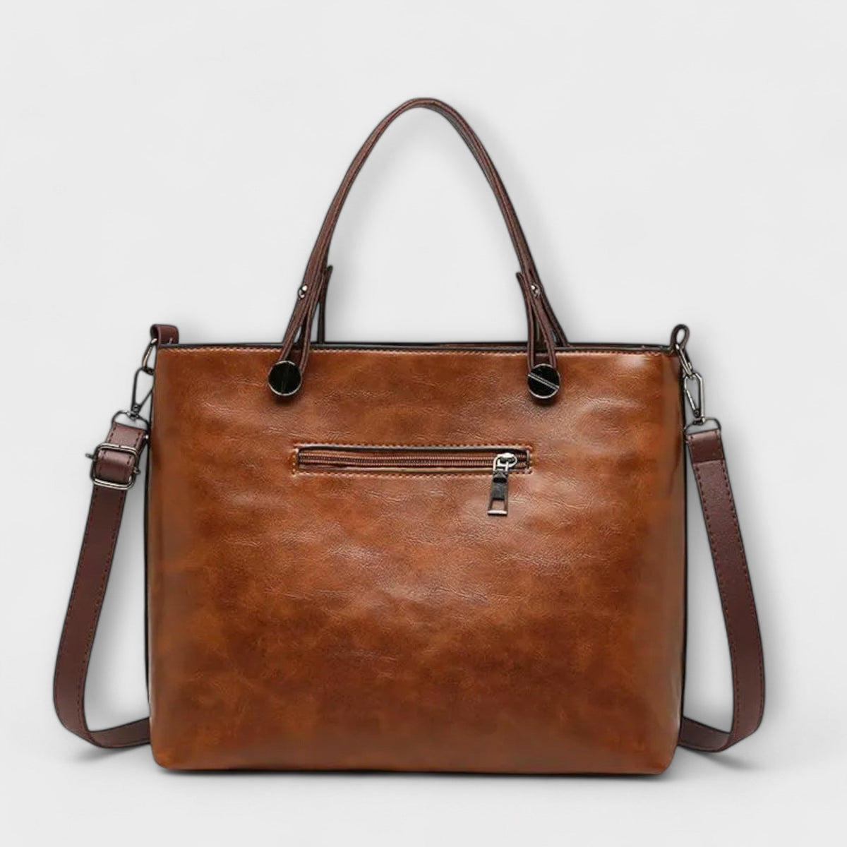 Brown leather tote bag with top handles, front center logo tab, and shoulder straps.