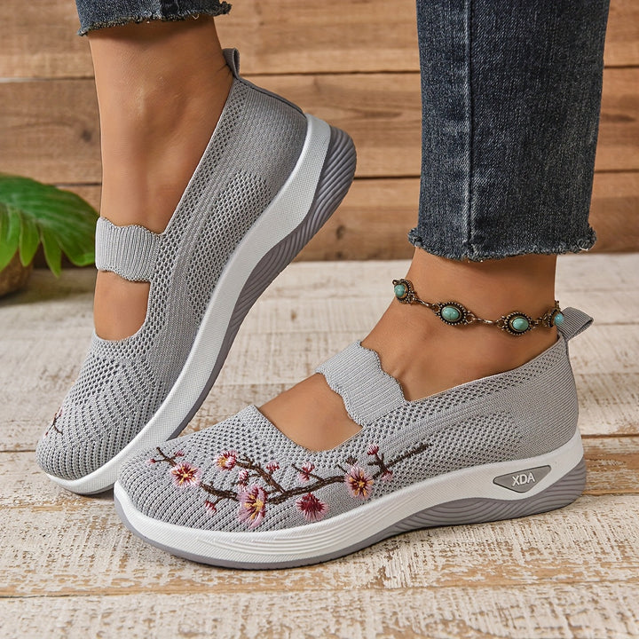 Gray knit slip-on orthopedic comfort shoes with floral stitching and wedge-style sole