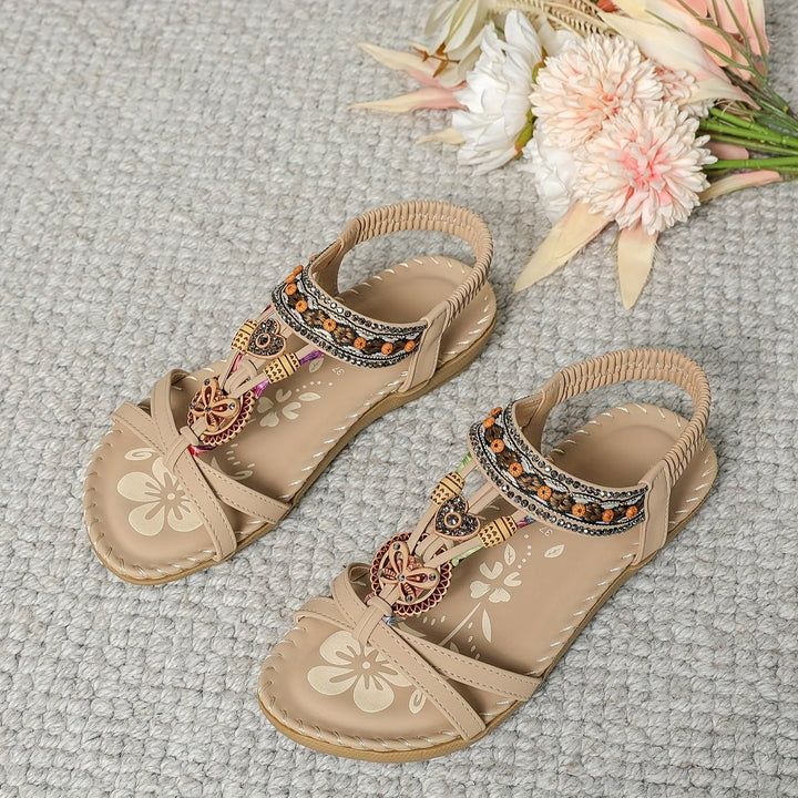 Beige boho flat sandals with open toe, bow-and-charm detail, beaded trim strap
