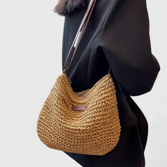 Tan woven crescent shoulder bag with brown strap and small logo patch