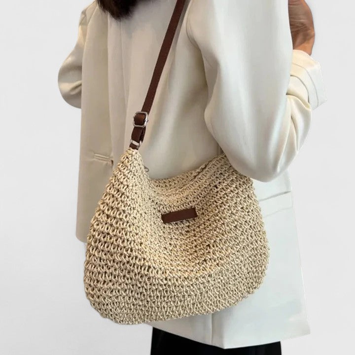 Beige woven half-moon shoulder bag with brown strap and front leather logo tab