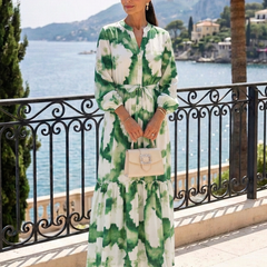 Long sleeve tie-waist tiered maxi dress in green and white floral print, standing