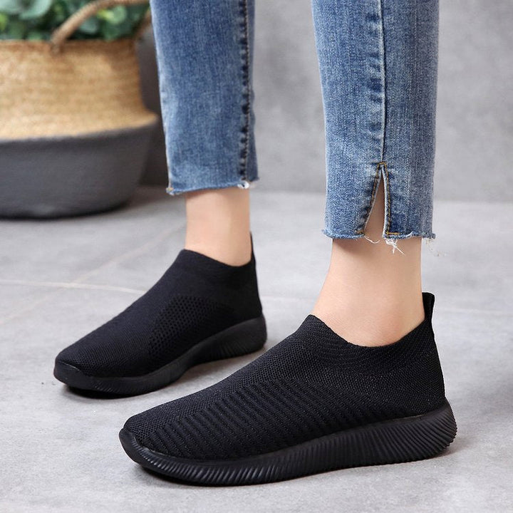 Black slip-on knit sneakers with cushioned sole and textured stretch upper