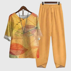 Two-piece set: mustard-orange short-sleeve top and matching pants, multicolor leaf artwork