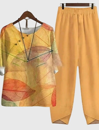 Two-piece set: mustard-orange short-sleeve top and matching pants, multicolor leaf artwork