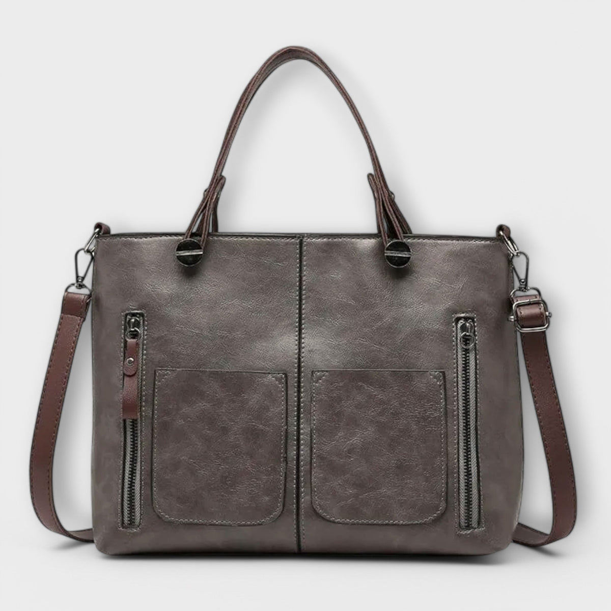 Gray leather tote bag with top handles, front pocket panels, and side zips.