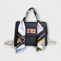Black handbag with gold clasp, chain strap, and patterned scarf handle