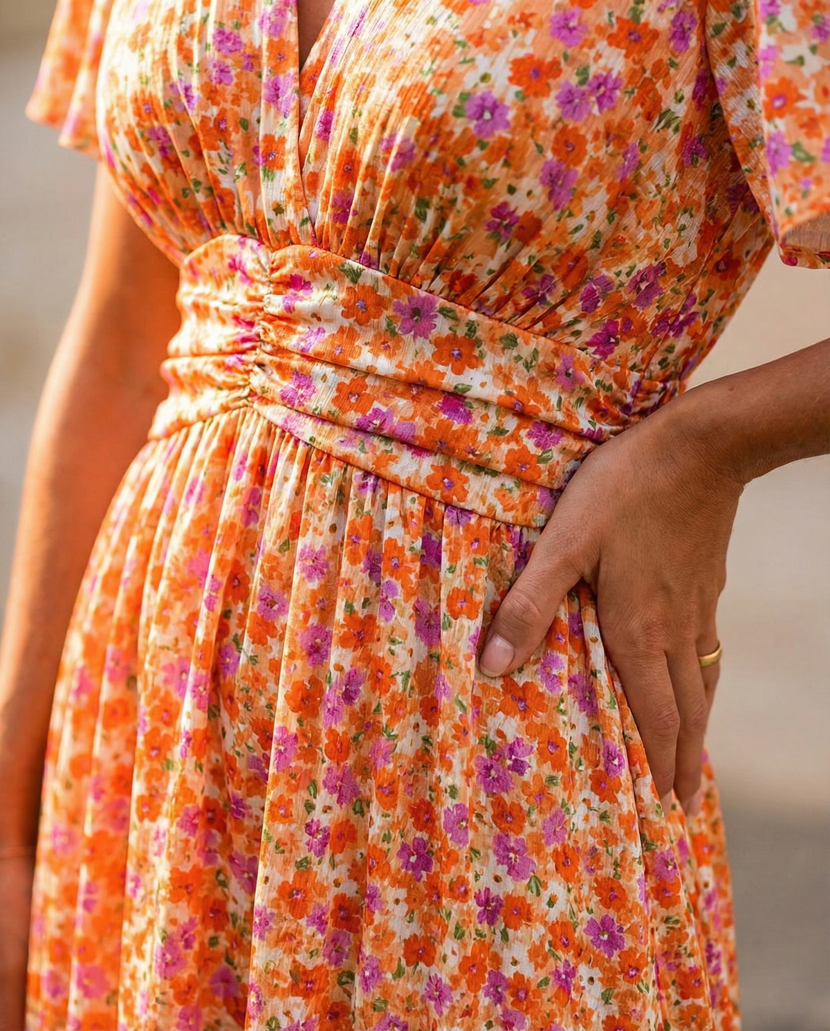 Front view close-up of orange floral dress with ruched waist and elastic gathering
