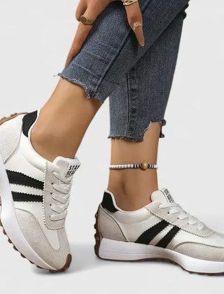 White lace-up orthopedic sneakers with black stripe accents and cushioned sole