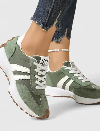 Green lace-up orthopedic sneakers with white stripe accents and cushioned sole